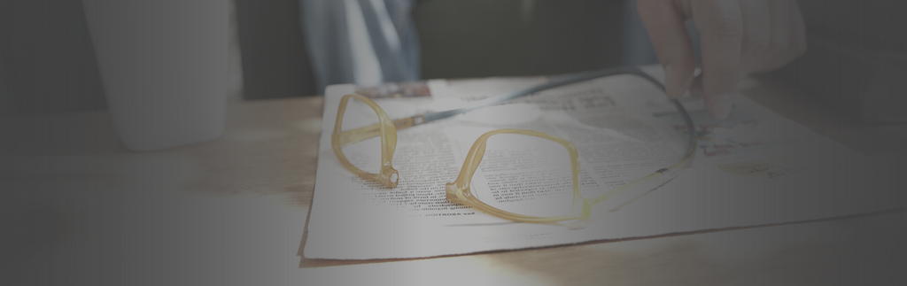 Person reaching for CliC magnetic readers on coffee table, glasses are sitting on a newspaper.